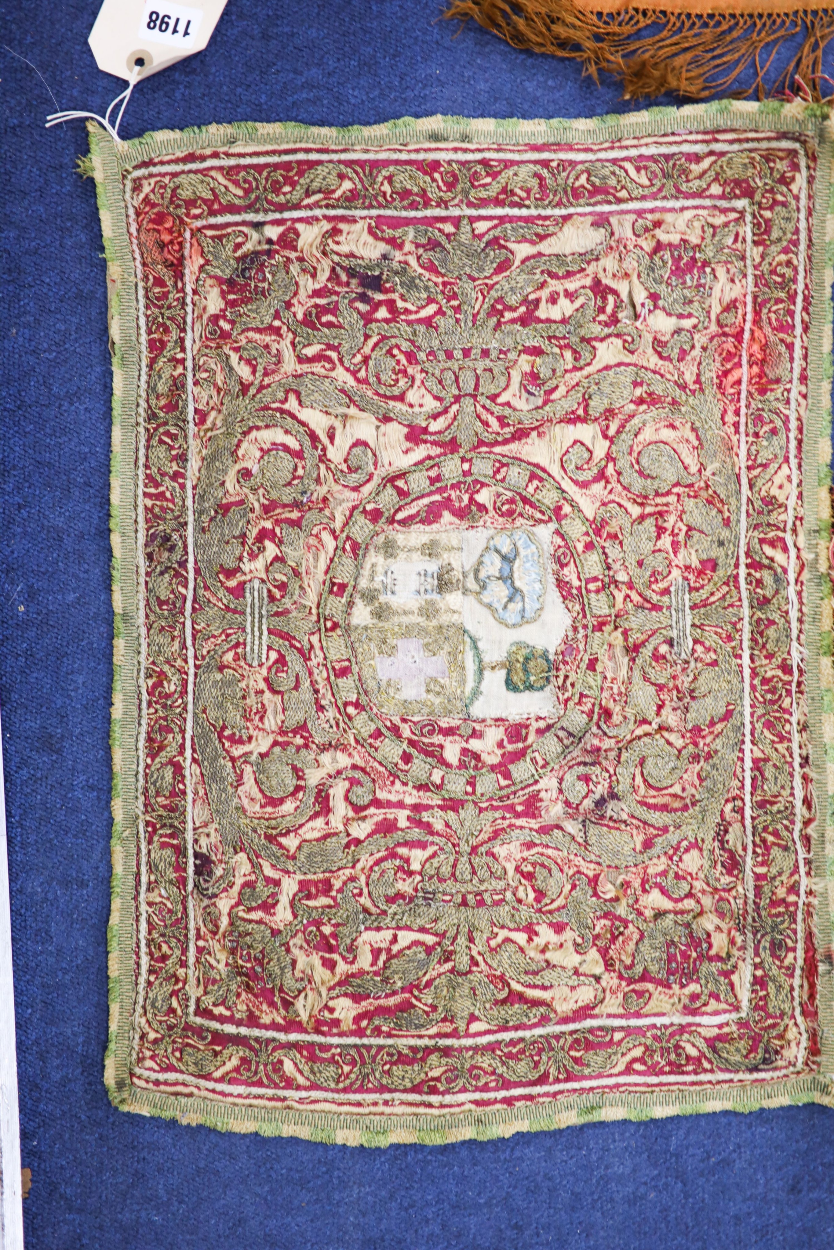 A Turkish / Persian embroidered silk panel with central armorial, 53 x 38cm. an embroidered silk hanging, 45 x 65cm and two cushions, 40 x 27cm.